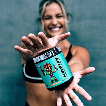 Smiling woman in gymwear holding Zombie Labs Molotov Thermogenic Energy Formula in Possessed Pine Mango flavour