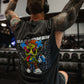 A muscular man with tattooed arms lifting weights in a gym, wearing a black Zombie Labs sleeveless tank top with a colorful cartoon character graphic and 'WEAREZOMBIE CROSSEYED' text on the back
